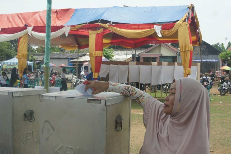 Salah seorang warga Desa Gintungkerta, Kecamatan Klari, Kabupaten Karawang, memasukkan surat suara yang telah dicoblos ke kotak suara, Minggu (11/11/2018).

