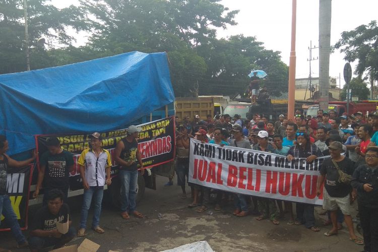 Asosiasi Armada Material Banyuwangi, menggelar aksi solidaritas  untuk membebaskan truk milik Hariyanto, rekannya yang ditahan karena memuat material pasir dari tambang pasir ilegal Senin (4/2/2019)