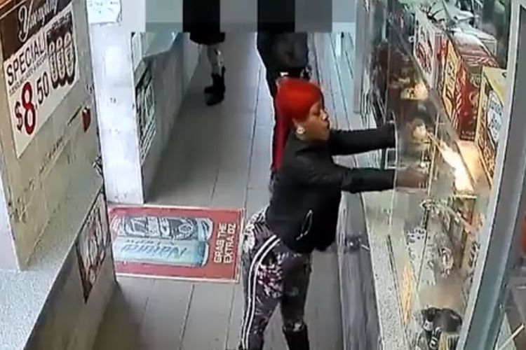 Potongan rekaman kamera pengawas menunjukkan perempuan berambut merah yang menyemprotkan obor api ke kasir sebuah kedai.