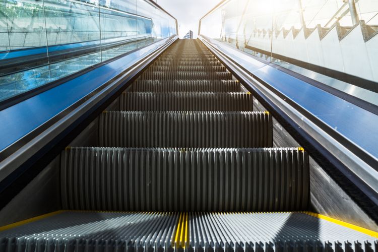 Escalator in an underground station with skyline in background.