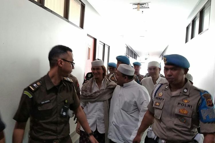 Tampak Bahar bin Smith tengah mendapatkan pengawalan dari petugas kepolisian saat memasuki ruang sidang yang berlokasi di Kantor Dinas Perpustakaan dan Arsip Kota Bandung, Jawa Barat, Kamis (28/3/2019).