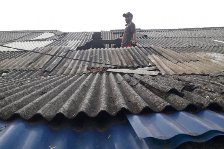 Warga bergotong-royong membereskan atap yang berterbangan akibat angin kencang di Semper Barat, Selasa (9/10/2018).