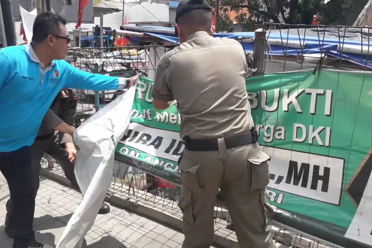 Petugas mencopot salah satu spanduk kampanye yang terpasang di Jalan Yos Sudarso, Jakarta Utara, Rabu (13/3/2019).