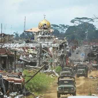 Mobil militer tampak melewati jalanan yang dihiasi dengan reruntuhan bangunan di Marawi, Filipina. (AFP/Ted Aljibe)