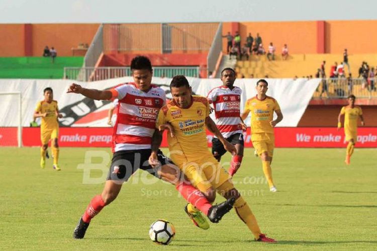 Bek Madura United, Fachruddin Aryanto, berduel dengan penyerang Sriwijaya FC, Beto Goncalves, dalam laga Liga 1 2018 yang bergulir di Stadion Pamekasan, Sabtu (7/4/2018).
