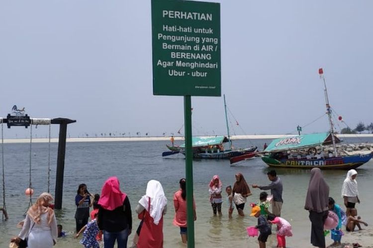 Manajemen PT Pembangunan Jaya Ancol Tbk memasang papan peringatan untuk para pengunjung pantai Ancol, Jakarta Utara agar menghindari ubur-ubur. Foto diambil Minggu (14/10/2018). 