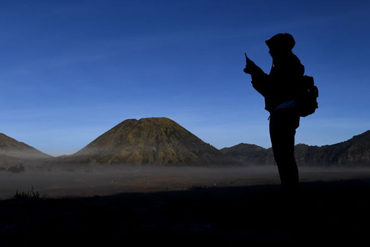 Pengunjung mengambil gambar hamparan pasir yang diselimuti empun upas dengan gawai miliknya di kawasan Gunung Bromo, Probolinggo, Jawa Timur, Minggu (30/6/2019). Fenomena embun upas tersebut disebabkan penurunan suhu yang mencapai 0 derajat celcius pada malam hari. 