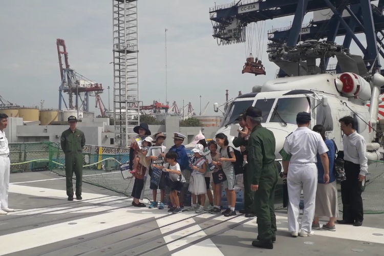 Pengunjung berpose di depan helikopter yang terparkir di buritan Kapal JS Suzutsuki, Kamis (20/9/2018).