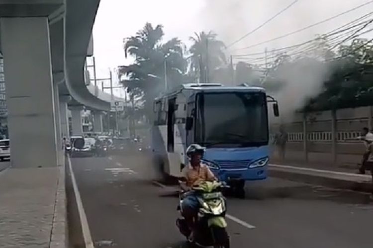 Sebuah bus transjakarta mengeluarkan asap tebal di depan ITC Fatmawati, Jakarta Selatan, Senin (21/1/2019) siang. Warga sekitar menyiram bus itu dengan air agar berhenti berasap.