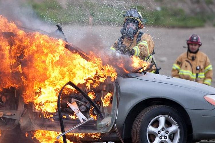 Ilustrasi: petugas berusaha memadamkan kobaran api pada mobil.