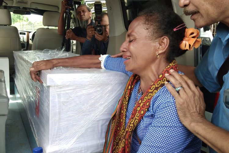 Salah seorang kerabat TKI Adelina, saat menangis dan memegang peti jenazah Adelina yang dimasukan ke dalam mobil jenazah di Bandara El Tari Kupang, Sabtu (17/2/2018)