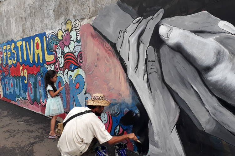 Sam Herry tampak hendak menggambar mural bertema Mural Islami di Gang Abdul Jabar, Kelurahan Jagakarsa, Jakarta Selatan, Rabu (23/5/2018) sore. Seorang anak perempuan ikut menggambar di dinding tersebut.