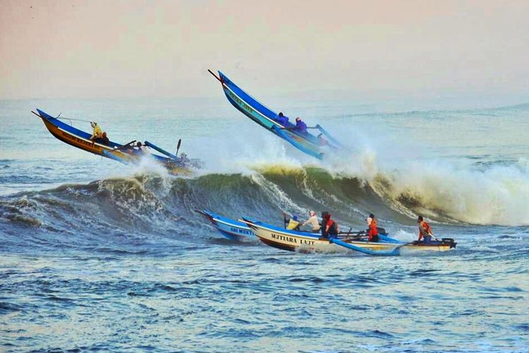 Perahu nelayan menerjang gelombang tinggi di perairan Teluk Penyu, Cilacap, Jawa Tengah.