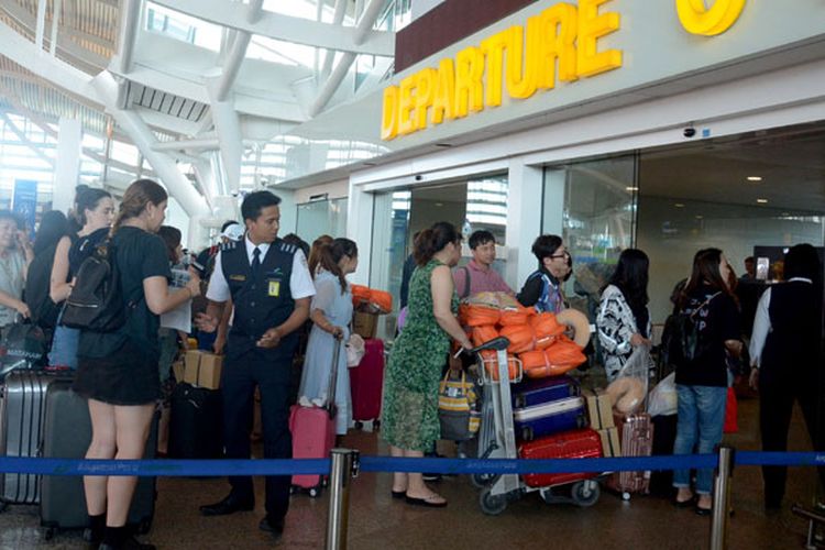 Sejumlah penumpang menunggu jadwal penerbangan di Bandara Ngurah Rai, Bali, Jumat (29/6/2018).  