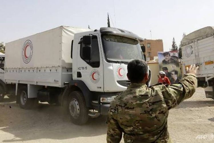 Pasukan rezim Suriah mengarahkan truk konvoi bantuan kemanusiaan dari Bulan Sabit Merah Arab Suriah di pos penjagaan al-Wafideen di pinggiran Damaskus yang berbatasan dengan wilayah Ghouta Timur, Senin (5/3/2018).