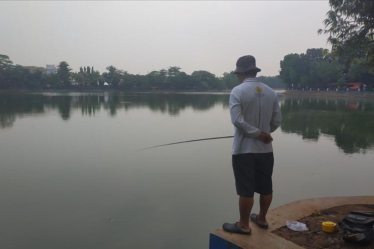 Seorang pria memancing di Setu Babakan, Jumat (17/5/2019).