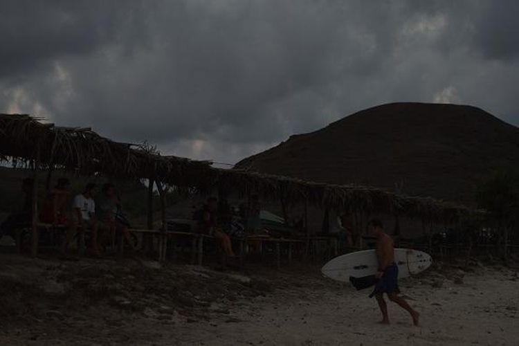 Seorang wisatawan mancanegara berjalan di pasir usai berselancar di Pantai Seger, Desa Kuta, Kecamatan Pujut, Lombok Tengah, Nusa Tenggara Barat, Jumat (20/11/2015) sore. Pantai Seger merupakan tempat berselancar bagi wisatawan yang telah memiliki keahlian.