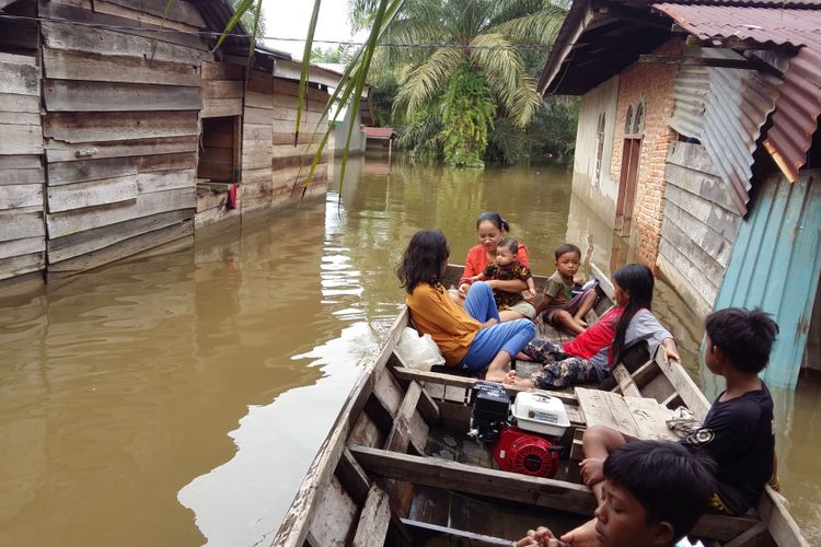 Warga menaiki sampan untuk keluar dari rumahnya yang telah terendam banjir dengan ketinggian mencapai satu meter lebih di Kabupaten Kampar