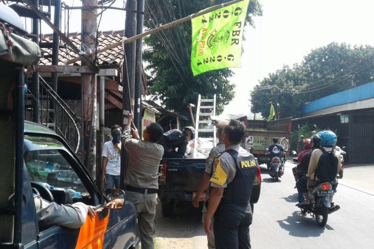 Petugas Satpol PP dan polisi mencopot bendera ormas di Ulujami, Jakarta Selatan, Kamis (27/7/2017).