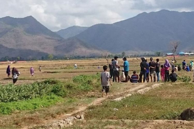Warga saat menyaksikan aksi saling serang dua kelompok warga yang terlibat bentrok di areal persawahan, perbatasan antar Desa Risa dan Dadibou, Kecamatan Woha, Kabupaten Bima, Rabu (18/17/2017).