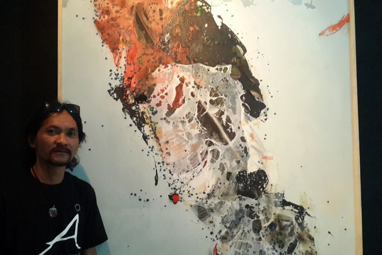 Masari Arifin, seniman lukis, saat berdiri di samping karyanya di Gedung Dewan Kesenian Malang (DKM), Selasa (5/12/2017). Lukisan itu terbuat dari medium plastik kresek dengan eksplorasi alat pemanas.