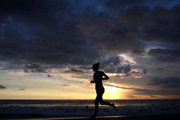 Seorang pelancong jogging di tepi pantai seiring terbenamnya matahari di anak-anak bermain-main di pantai saat senja di Seminyak, Bali, Sabtu (18/2/2017).
