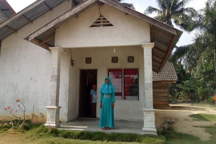 Ibu Asraf, Atik, berdiri di depan rumahnya yang sudah dibedah pemerintah setempat di Desa Bina Baru, Kecamatan Kampar Kiri Tengah, Kabupaten Kampar, Riau, Rabu (14/8/2019). Asraf salah satu Paskibraka nasional perwakilan Riau.