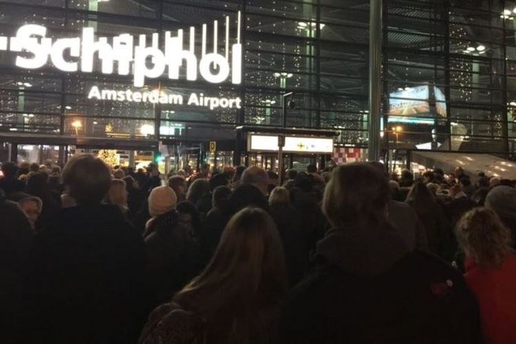 Para calon penumpang berkerumun di luar Bandara Schiphol Amsterdam setelah polisi menembak seorang pria yang mengancam staf kepolisian bandara menggunakan bandara (15/12/2017).