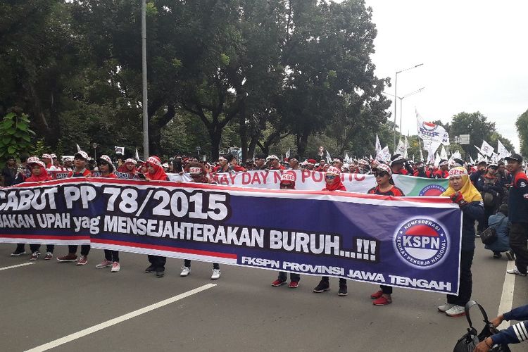 Massa peserta aksi Hari Buruh Internasional berunjuk rasa di Jalan Medan Merdeka Selatan dekat Monumen Nasional, Rabu (1/5/2019).