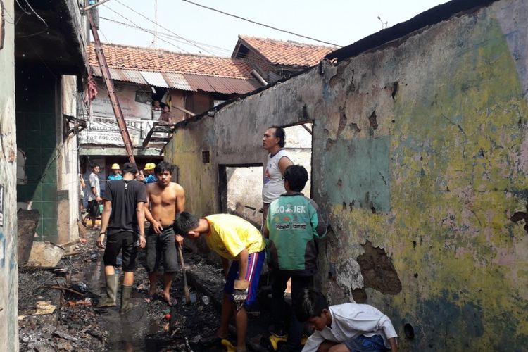 Sejumlah warga bergotong-royong mengais barang yang bisa diselamatkan dari lokasi kebakaran di kawasan Kali Baru, Jakarta Utara, Senin (13/8/2018).