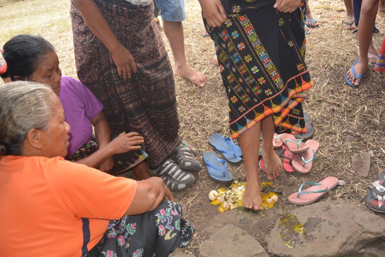 Seorang istri sedang injak telur ayam kampung atau kedha rugha manuk sebelum masuk di Mbaru Gendang atau rumah adat Suku Saghe, Jumat (2/11/2018).  