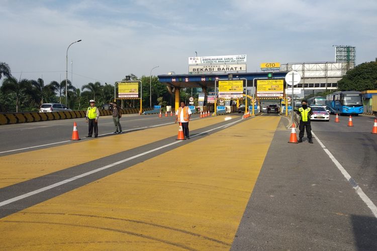 Petugas berjaga di depan gerbang tol Bekasi Barat dalam rangka pengawasan kebijakan ganjil genap