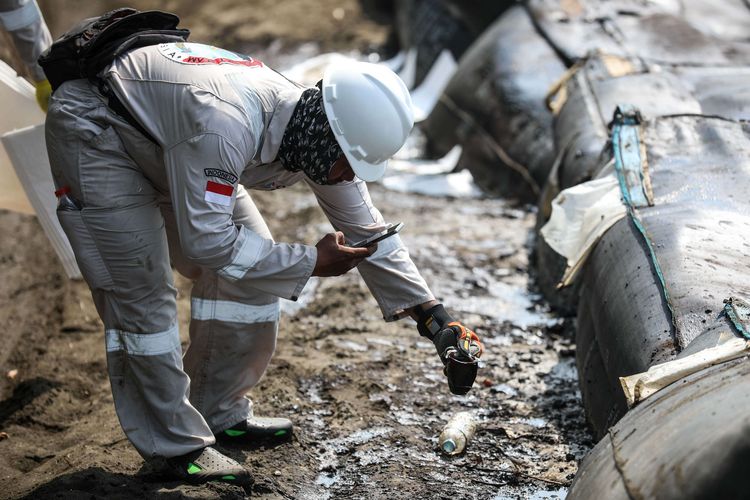 Petugas mengumpulkan limbah tumpahan minyak Oil Spill yang tercecer milik Pertamina di Pesisir Pantai Cemarajaya, Karawang, Jawa Barat, Minggu (4/8/2019). Pasir yang tercemar minyak tersebut dikumpulkan dan akan dipindahkan ke pabrik penyimpanan limbah B3 (Bahan Berbahaya dan Beracun) untuk dimusnahkan.