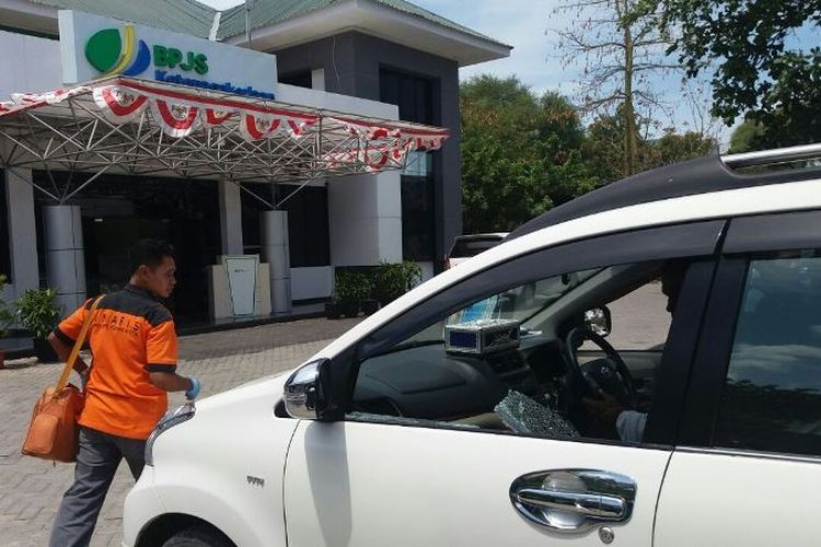 Polisi sedang melakukan olah tempat kejadian perkara di mobil Avanza berwarna putih milik Pendeta Yusak Holbala. Kaca mobil pecah dan uang Rp 120 juta dalam mobil raib.