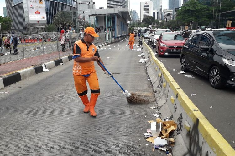Petugas PPSU membersihkan sampah yang ditinggalkan massa peserta aksi Hari Buruh Internasional di Jalan Jenderal Sudirman kawasan Tosari, Rabu (1/5/2019)?
