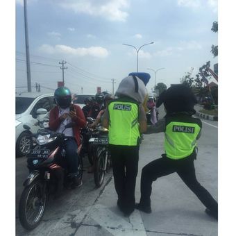 Dua polisi menghibur para pengendara yang melintas di kawasan Tol Fungsional Solo-Kertosono