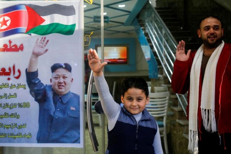 Salim Rabaa (kanan) berdiri di depan restorannya di Jalur Gaza yang dihiasi poster berisi ucapan terima kasih untuk Kim Jong Un.
