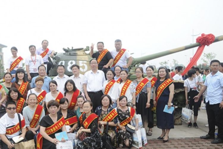 Staf pengajar sekolah di China berfoto di depan sebuah tank motivasi saat upacara masuk sekolah tahunan.