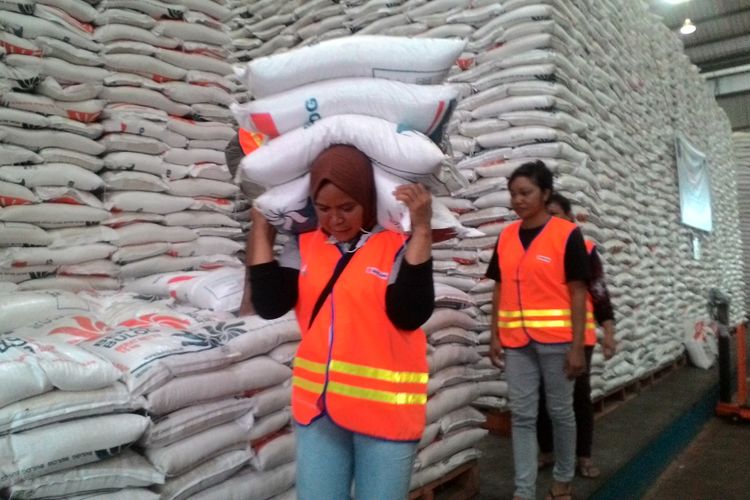 Aktifitas buruh wanita dapat memikul empat karung beras di gudang Bulog Panaikang, Makassar, Jumat (12/1/2018).