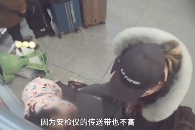 Tangkapan layar rekaman kamera pengawas menunjukkan saat seorang gadis naik ke mesin x-ray di stasiun kereta di China.