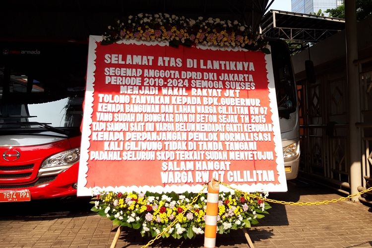 Karangan bunga dari warga RW 07, Cililitan, Jakarta Timur yang memberikan ucapan selamat atas pelantikan DPRD DKI dan menyindir Gubernur DKI Jakarta Anies Baswedan terkait ganti rugi normalisasi, di Gedung DPRD DKI, Jalan Kebon Sirih, Jumat (30/8/2019)