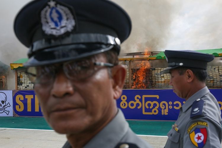 Polisi Myanmar berjaga di dekat tumpukan barang bukti narkoba yang dibakar saat Hari Anti-narkoba Sedunia di Yangon, pada 26 Juni 2017.