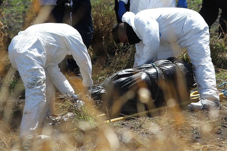 Petugas forensik dari satuan kepolisian Meksiko saat memeriksa temuan kantong plastik di saluran pembuangan di negara bagian Jalisco, yang berisi potongan 19 jenazah.