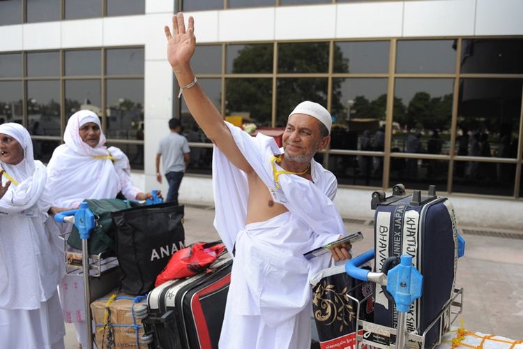 Jamaah haji asal India melambaikan tangan ke arah keluarga yang mengantar saat di bandara internasional Sardar Vallabhbhai Patel di Ahmedabad, Oktober 2010.