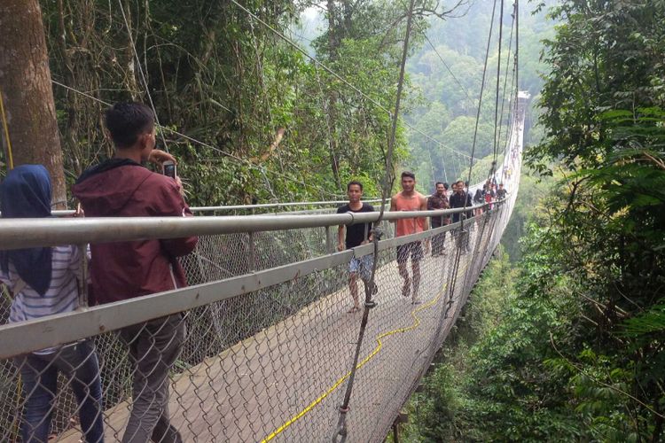 Sejumlah wisatawan melintas jembatan gantung di Taman Nasional Gunung Gede Pangrango (TNGGP) Resort Situgunung, Kadudampit, Sukabumi, Jawa Barat, Minggu (17/6/2018).
