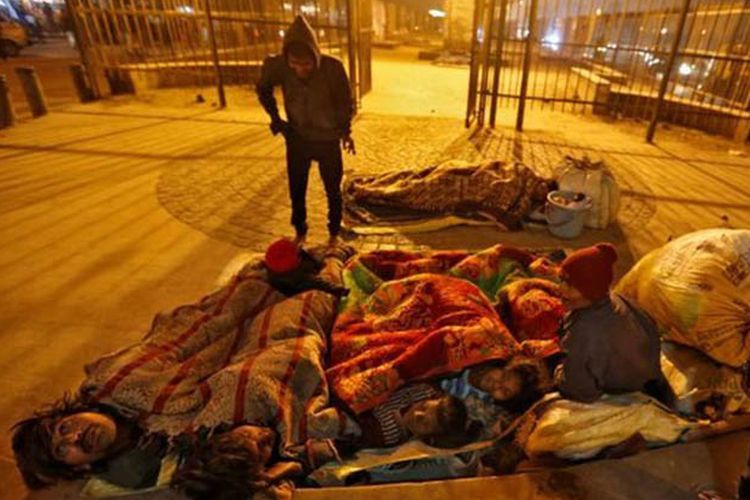 Keluarga tunawisma menggunakan selimut dan tidur di bawah jalan layang untuk melindungi mereka dari hawa dingin di New Delhi, India.