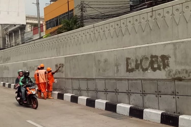 Petugas penanganan prasarana dan sarana umum (PPSU) Kelurahan Mampang Prapatan membersihkan coretan-coretan dari cat piloks di dinding underpass Mampang-Kuningan, Jakarta Selatan, Minggu (3/6/2018).