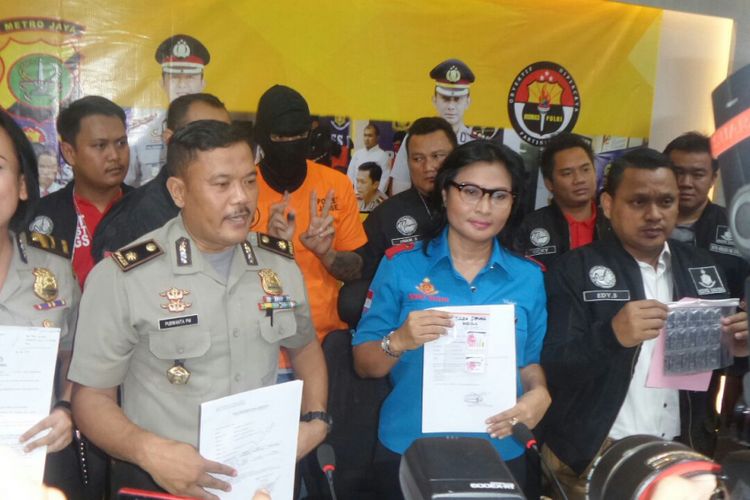 Polisi menunjukkan barang bukti berupa tablet dumolid dan hasil tes urine Tora Sudiro dalam konferensi pers di Polres Metro Jakarta Selatan, Jumat (4/8/2018). Tora yang mengenakan baju tahanan berwarna oranye dan penutup kepala tampak berdiri di baris belakang.