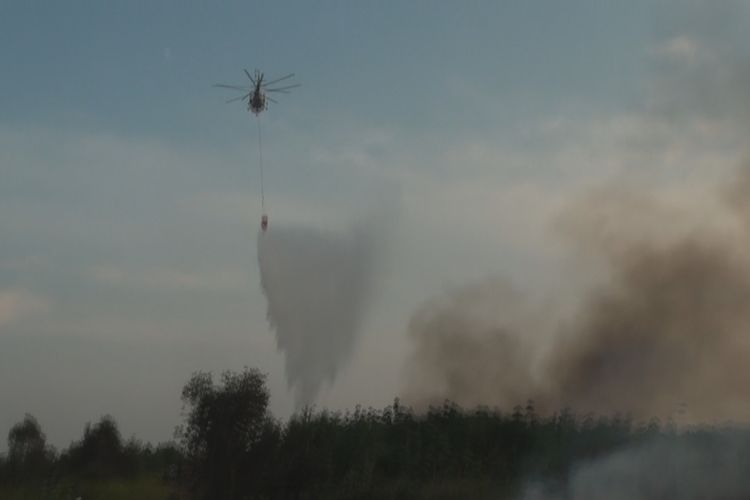Sebuah helikopter water bombing tampak menumpahkan air ke lokasi lahan yangt terbakar di Desa Kayuara Batu Muaraenim