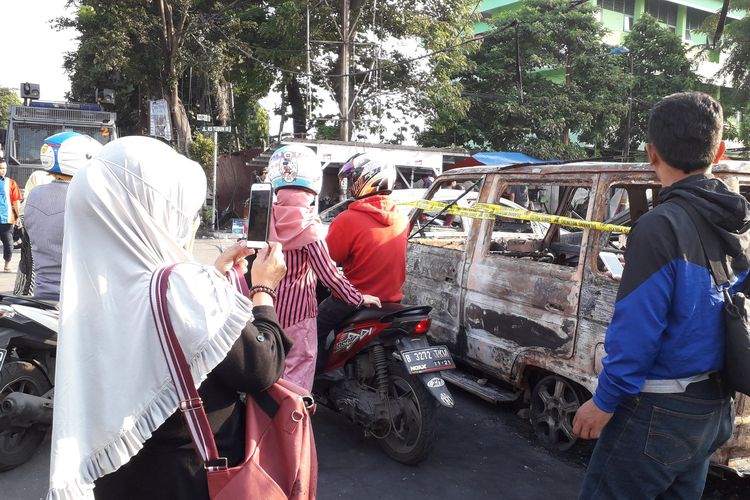 Sejumlah warga yang melintas memotret mobil yang terbakar akibat kerusuhan di Petamburan, Jakarta Barat pada Rabu (22/05/2019).